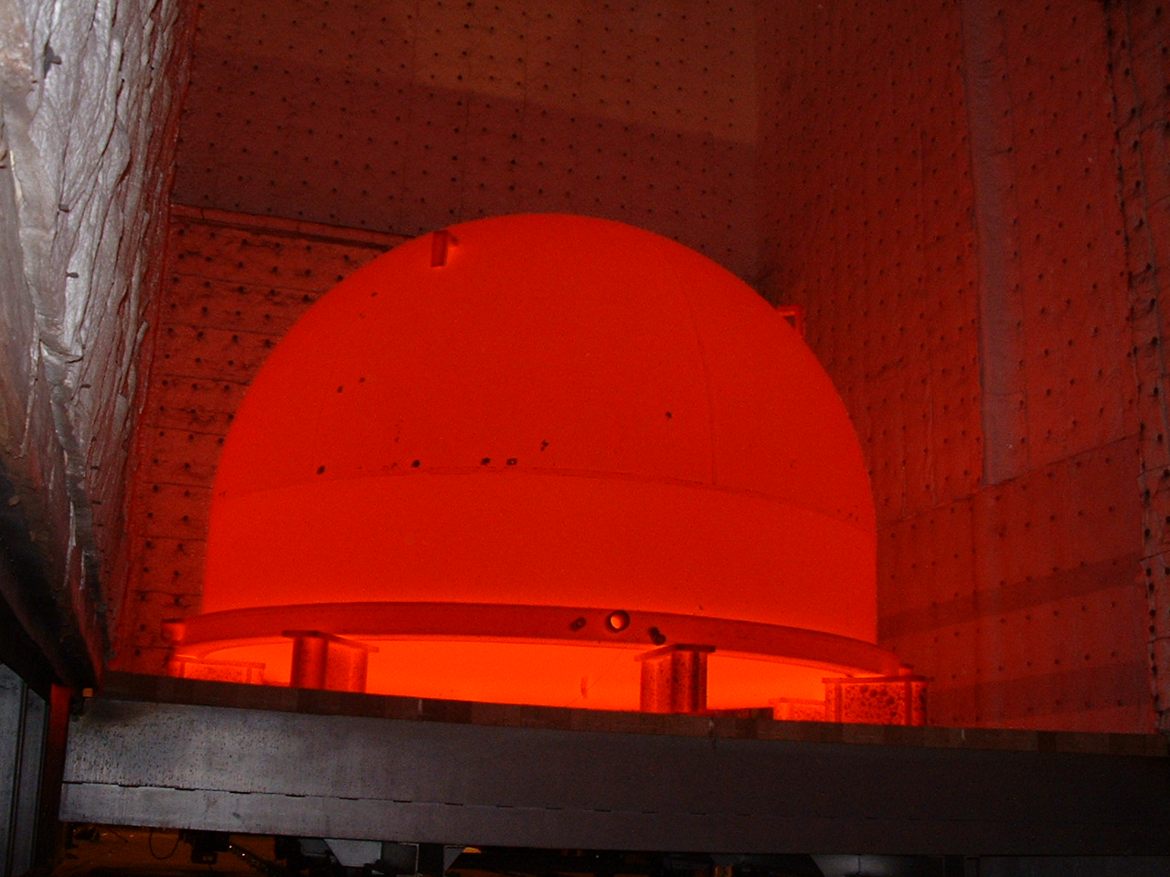 A steel fabrication glowing red during controlled in-house heat treatment